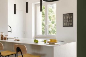 Kuchyňský ostrůvek s barovými židlemi a epoxidovou podlahou který tvoří přirozené centrum otevřeného obytného prostoru.