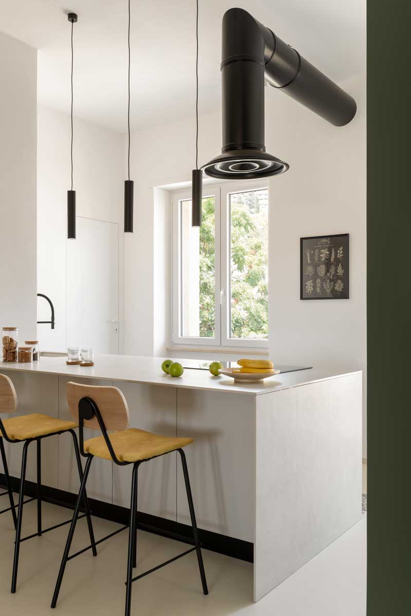 Kuchyňský ostrůvek s barovými židlemi a epoxidovou podlahou který tvoří přirozené centrum otevřeného obytného prostoru.