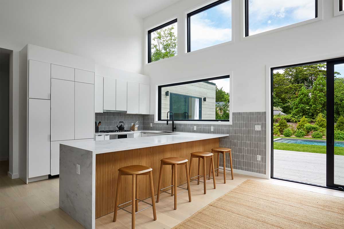 Kuchyňský ostrůvek s dřevěnými detaily a barovým sezením vytváří přirozené centrum domácnosti.