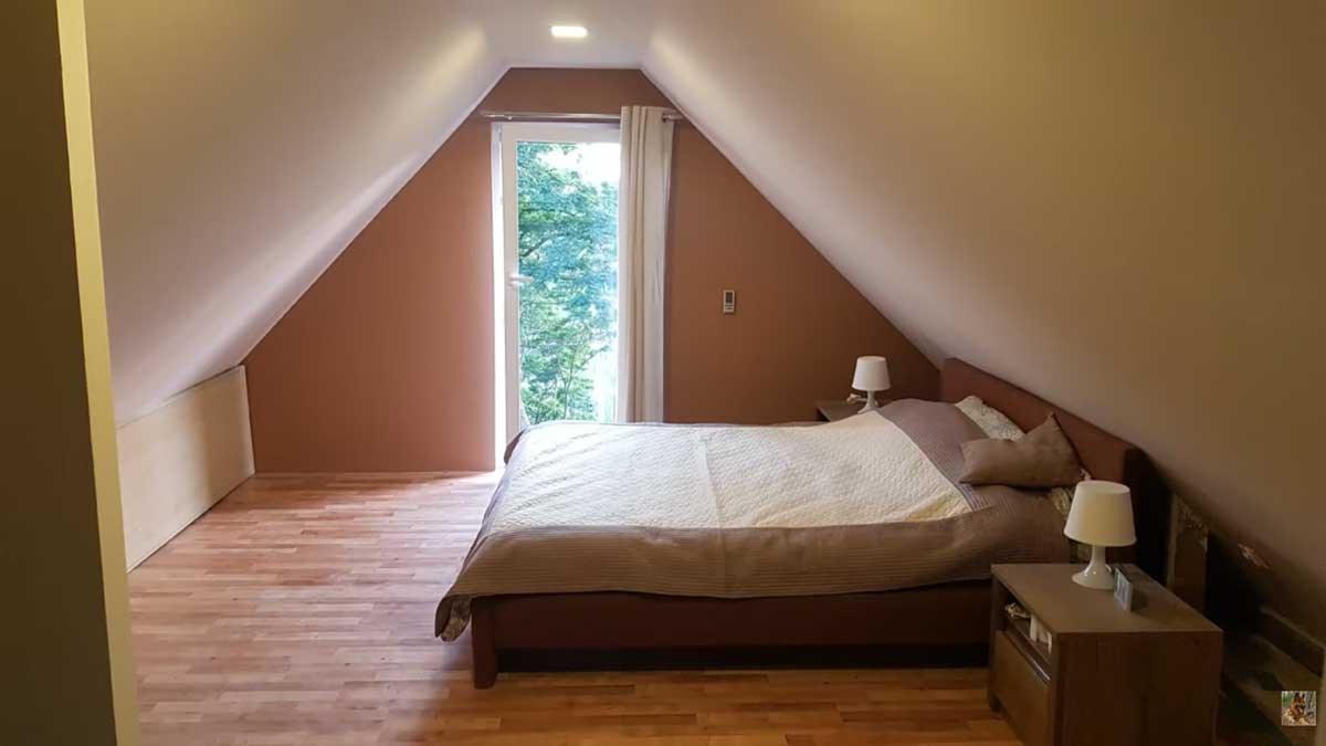Minimalistická ložnice v podkroví se šikmým stropem a velkým oknem