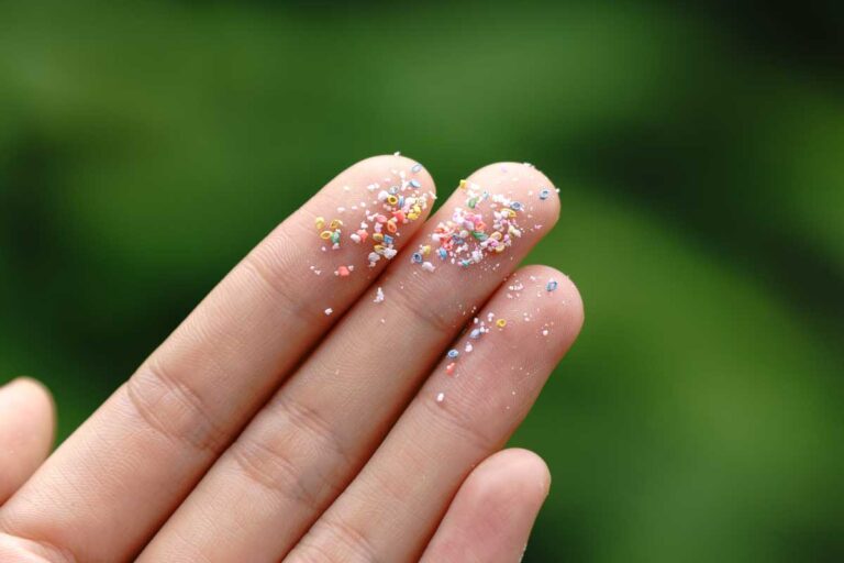 Detail mikroplastů na ruce jako ukázka neviditelných částic v domácnosti.