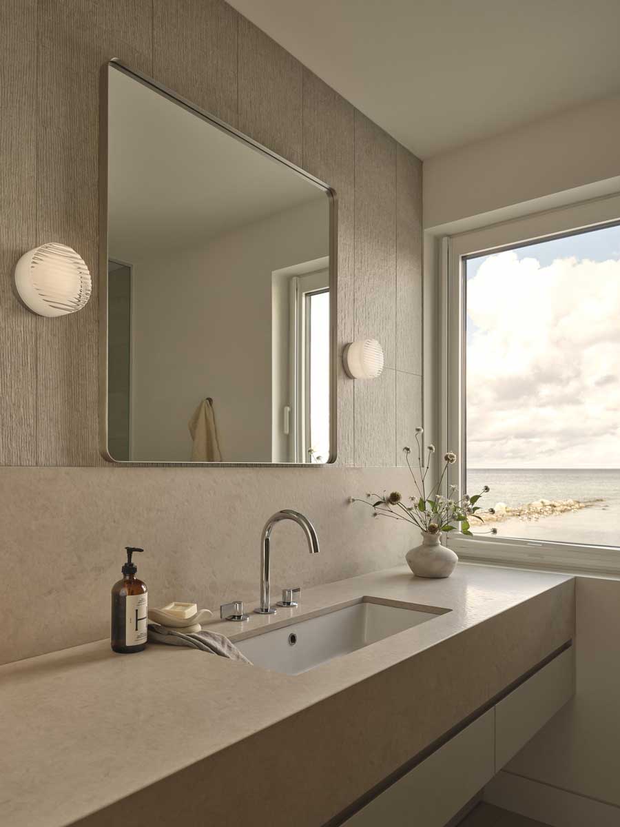 Moderní koupelna s kamennou deskou a velkým zrcadlem působí čistě a nadčasově