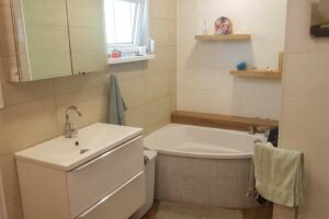 Světlá koupelna s rohovou vanou a moderním umyvadlem po rekonstrukci