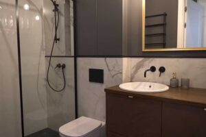 Nová koupelna s walk in sprchou, dřevěnou skříňkou a velkým zrcadlem v moderním industriálním stylu.