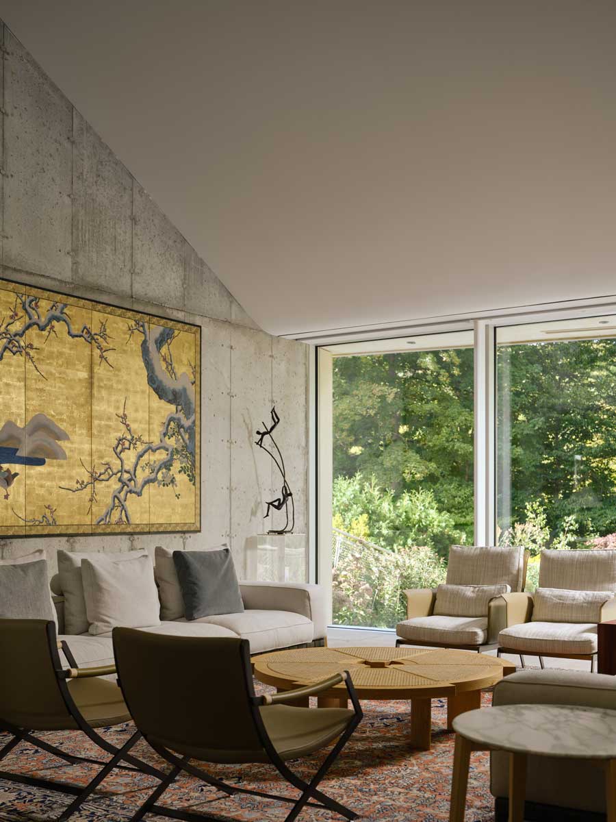 Obývací pokoj s velkým obrazem, betonovou stěnou a výhledem do zeleně