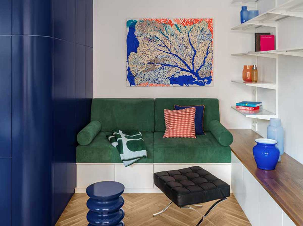 Obývací pokoj s modrým vestavěným nábytkem policemi a zelenou pohovkou v bytě architektů