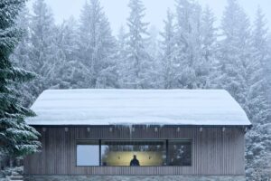 Velké okno s výhledem do lesa propojující interiér s okolní přírodou