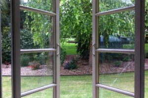 Otevřená okna v bytě směřující do zahrady kde se na skle usazuje méně prachu