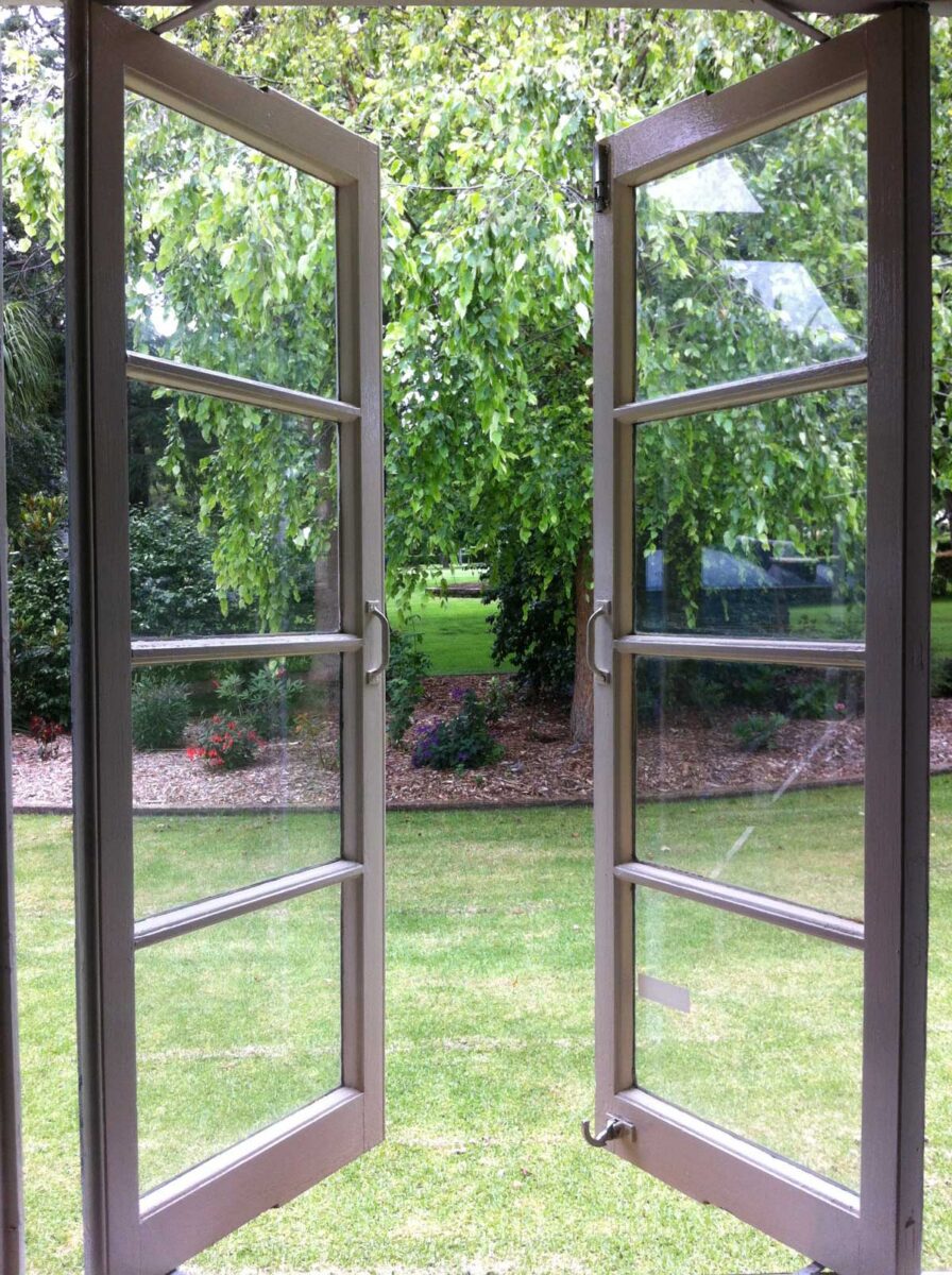 Otevřená okna v bytě směřující do zahrady kde se na skle usazuje méně prachu