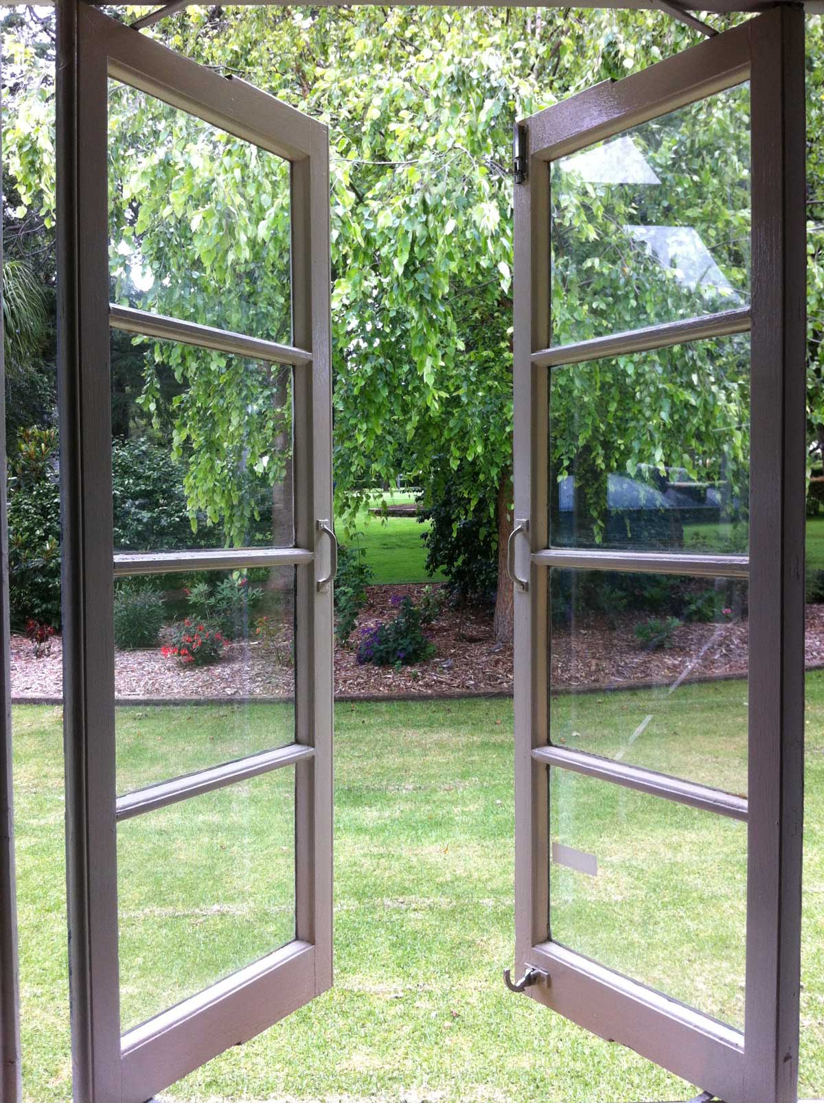 Otevřená okna v bytě směřující do zahrady kde se na skle usazuje méně prachu