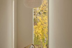 Dřevěné schodiště s velkým oknem propojuje interiér s venkovní scenérií a přivádí dovnitř světlo