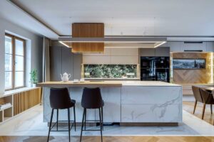 Kuchyňský ostrůvek s barovým pultem keramickým obkladem v dekoru kamene a dvěma vysokými židlemi.