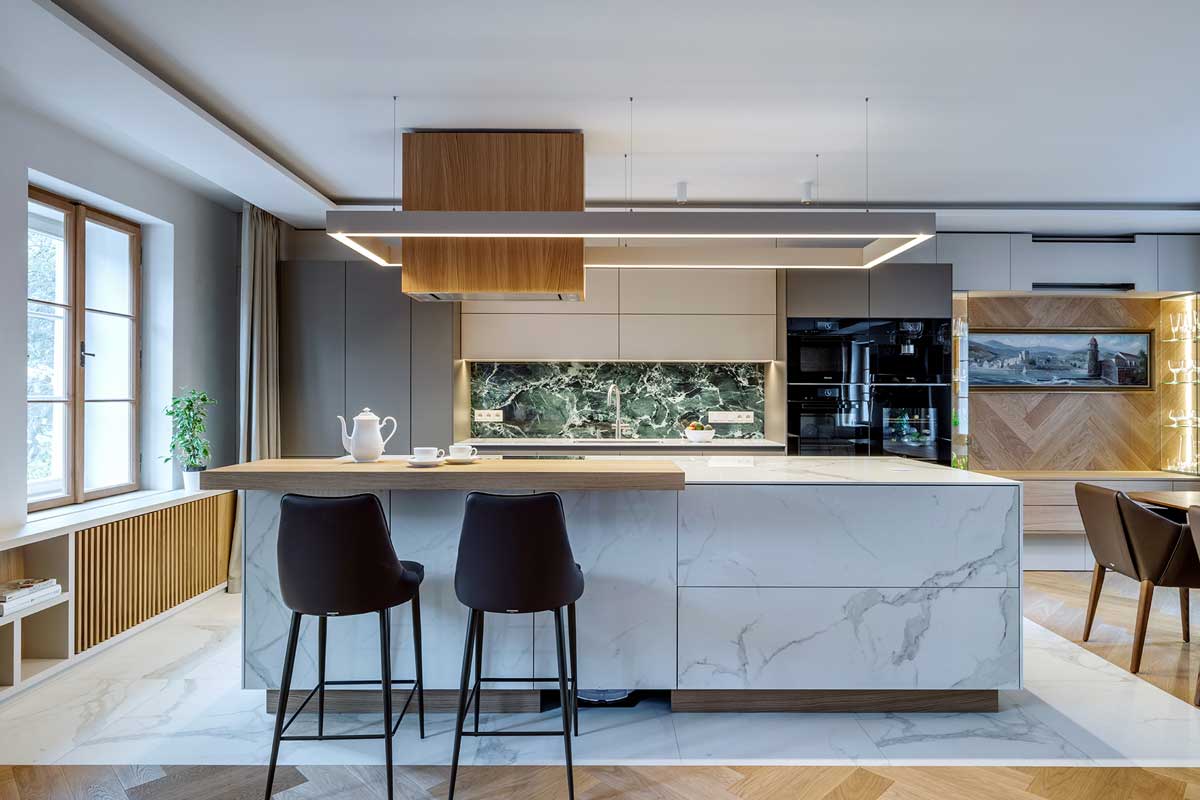 Kuchyňský ostrůvek s barovým pultem keramickým obkladem v dekoru kamene a dvěma vysokými židlemi.