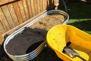 Plnění vyvýšeného záhonu substrátem a organickým materiálem během zakládání