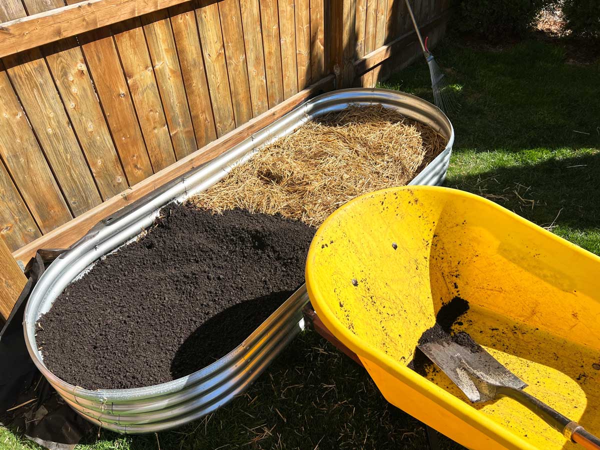 Plnění vyvýšeného záhonu substrátem a organickým materiálem během zakládání