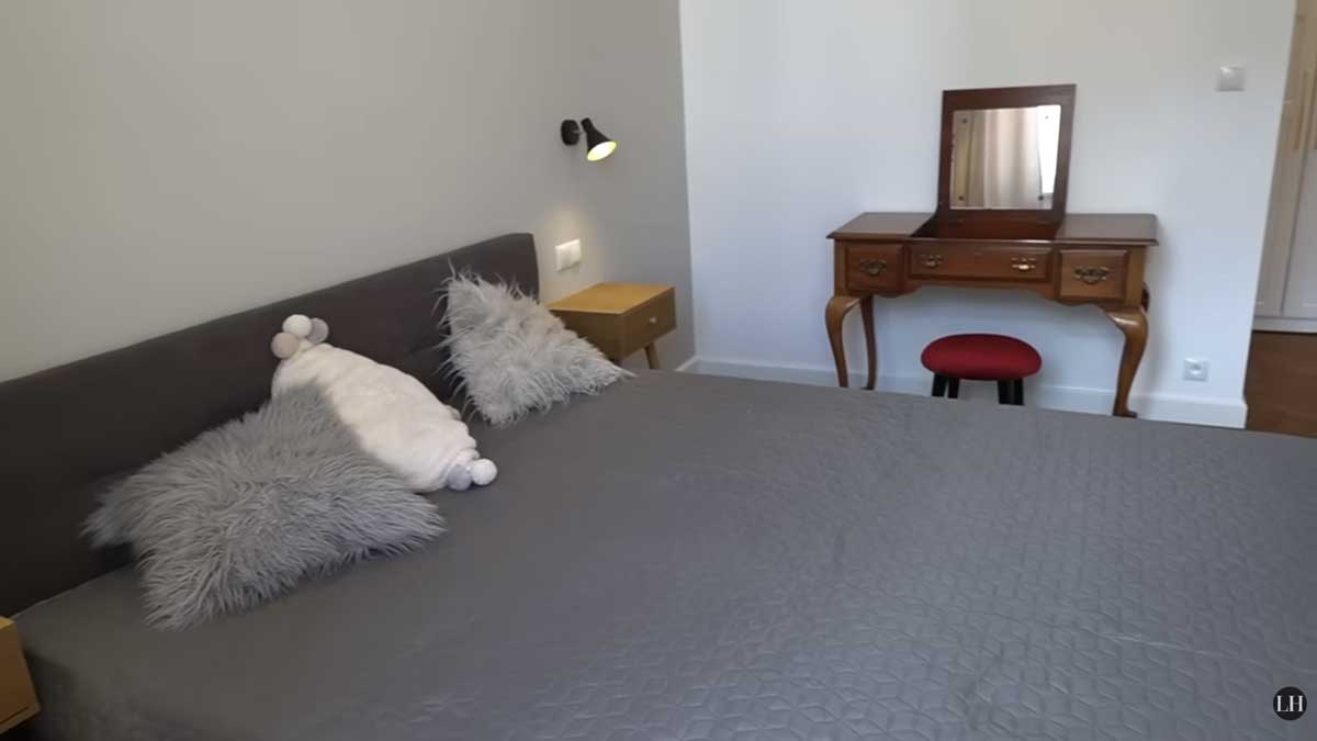 Ložnice po rekonstrukci s jednoduchou postelí, nočními stolky a elegantním toaletním stolkem z tmavého dřeva.