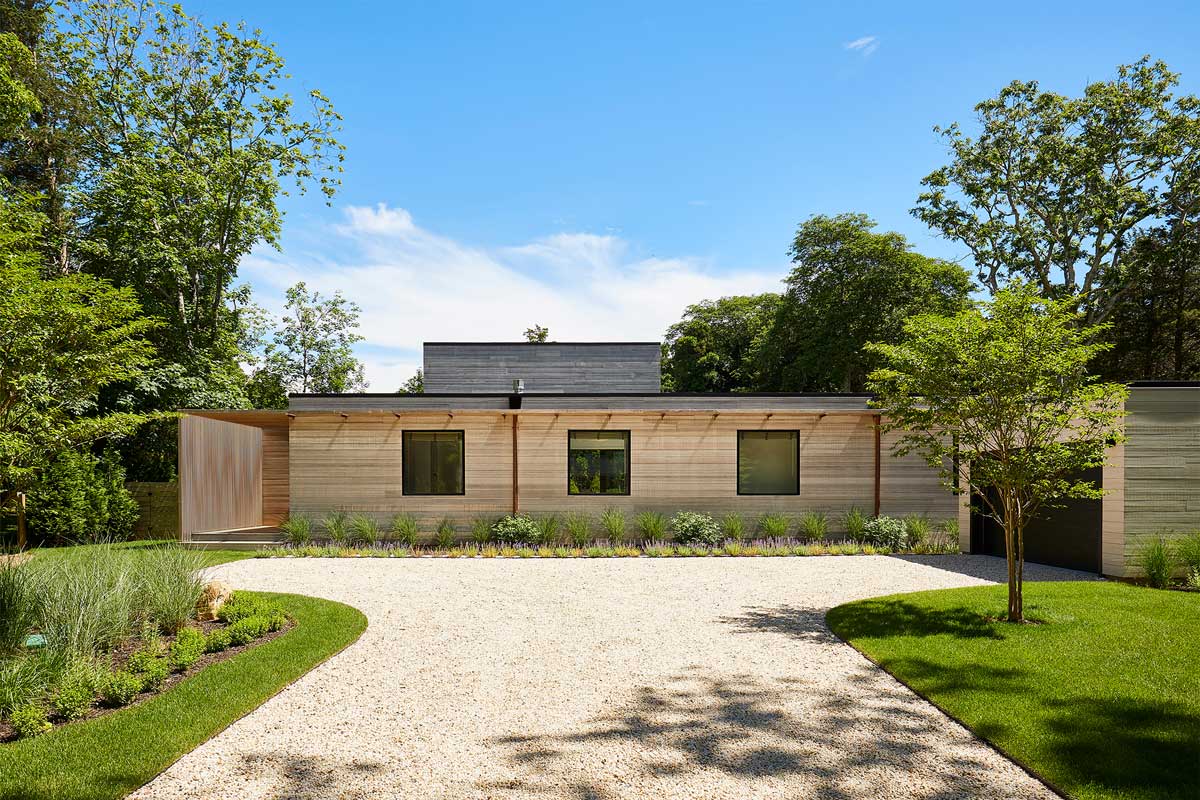 Příjezdová část domu se štěrkovou plochou a výsadbou okrasných trav působí přirozeně a nenápadně.