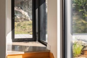Prosklené dveře vedoucí z interiéru přímo do svahu s výhledem na skály a zeleň.