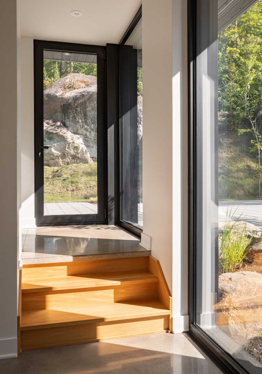 Prosklené dveře vedoucí z interiéru přímo do svahu s výhledem na skály a zeleň.