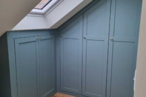 Vestavěné skříňky pod střešním oknem efektivně využívají šikmou stěnu podkroví.