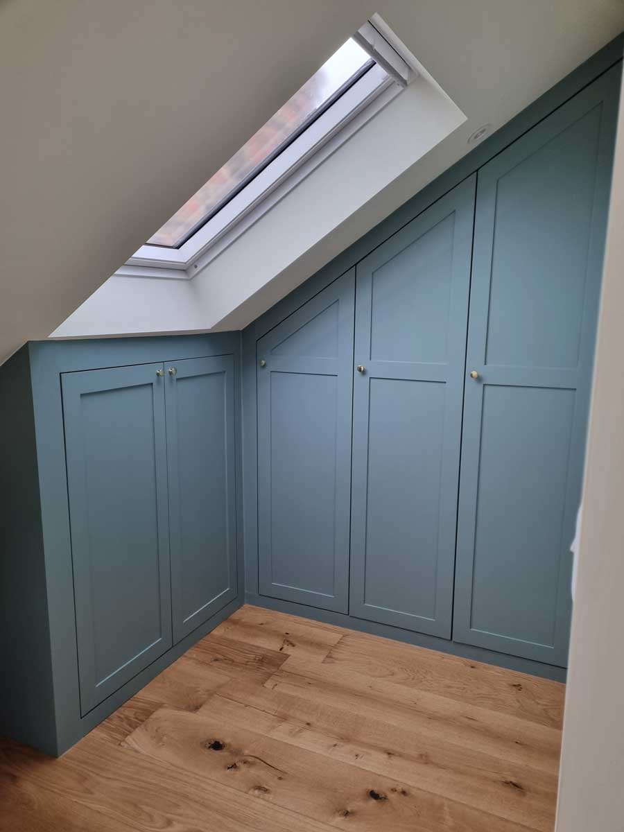 Vestavěné skříňky pod střešním oknem efektivně využívají šikmou stěnu podkroví.