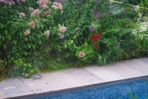 Přírodní výsadba u bazénu s trvalkami a divokým charakterem zahrady