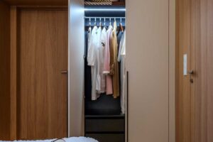 Vestavěná šatní skříň v ložnici s béžovými dvířky přírodní dýhou a vnitřním podsvícením.