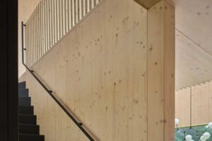 Schodiště v dřevěném interiéru vedoucí na galerii s otevřeným prostorem