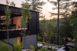 Kamenné schody a zahradní cesty na svažitém pozemku u domu obklopeného lesem.