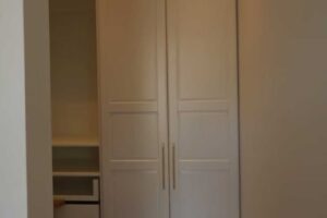 Skrytá šatna za nenápadnými dveřmi, které vypadají jako běžná vestavěná skříň v ložnici.
