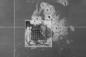 Špinavý sprchový odtok s pěnou a usazeninami před čištěním.