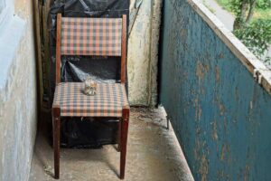 Starý rozviklaný nábytek odložený na balkoně místo odpočinkové zóny