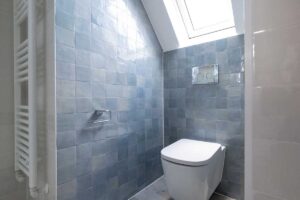 Malá koupelna se světlými obklady doplněnými jemným modrým tónem