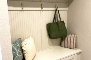 Vestavěná lavice s úložnými skříňkami a nástěnnými háčky vytváří praktickou zónu v předsíni.