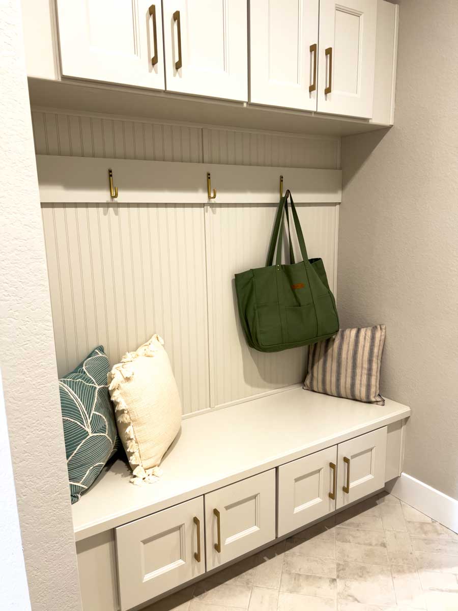 Vestavěná lavice s úložnými skříňkami a nástěnnými háčky vytváří praktickou zónu v předsíni.