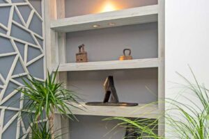 Vestavěné police ve výklenku s decentním podsvícením a dekorativními předměty.