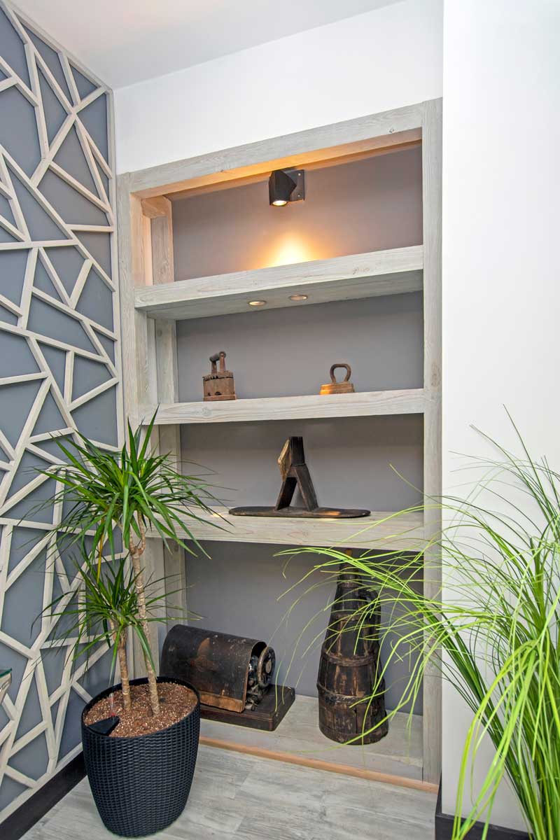 Vestavěné police ve výklenku s decentním podsvícením a dekorativními předměty.