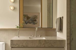 Minimalistická koupelna s kamenným umyvadlem a velkým zrcadlem působí klidně a harmonicky