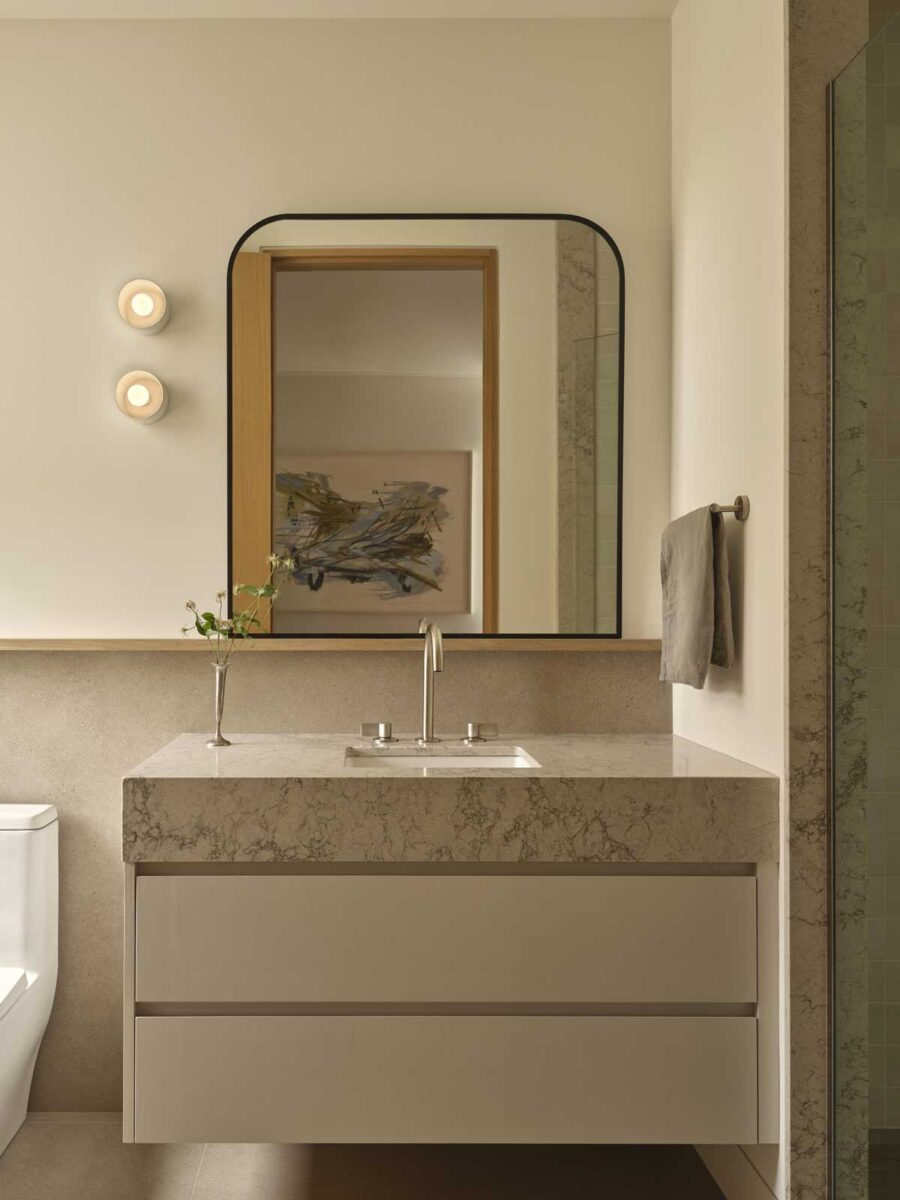 Minimalistická koupelna s kamenným umyvadlem a velkým zrcadlem působí klidně a harmonicky