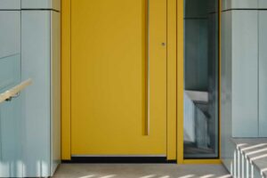 Vstupní část domu se žlutými dveřmi a jemně strukturovanou fasádou