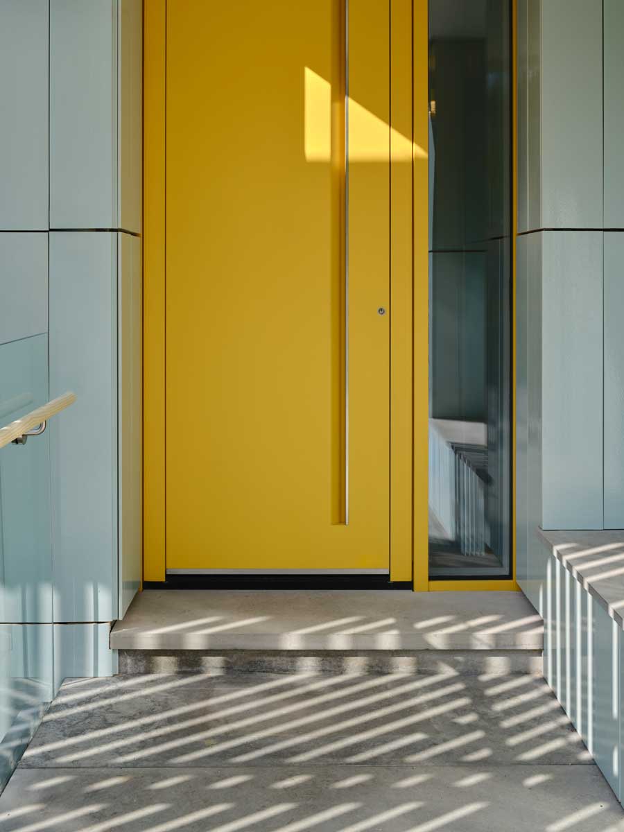 Vstupní část domu se žlutými dveřmi a jemně strukturovanou fasádou