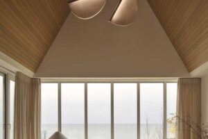 Obývací prostor s velkými okny otevírá interiér směrem k jezeru a propojuje dům s okolní krajinou