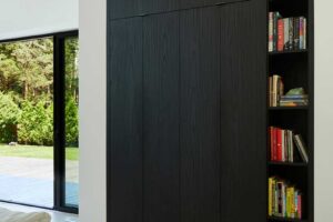 Vestavěná skříň v tmavém dřevě kombinuje úložný prostor s otevřenou knihovnou.