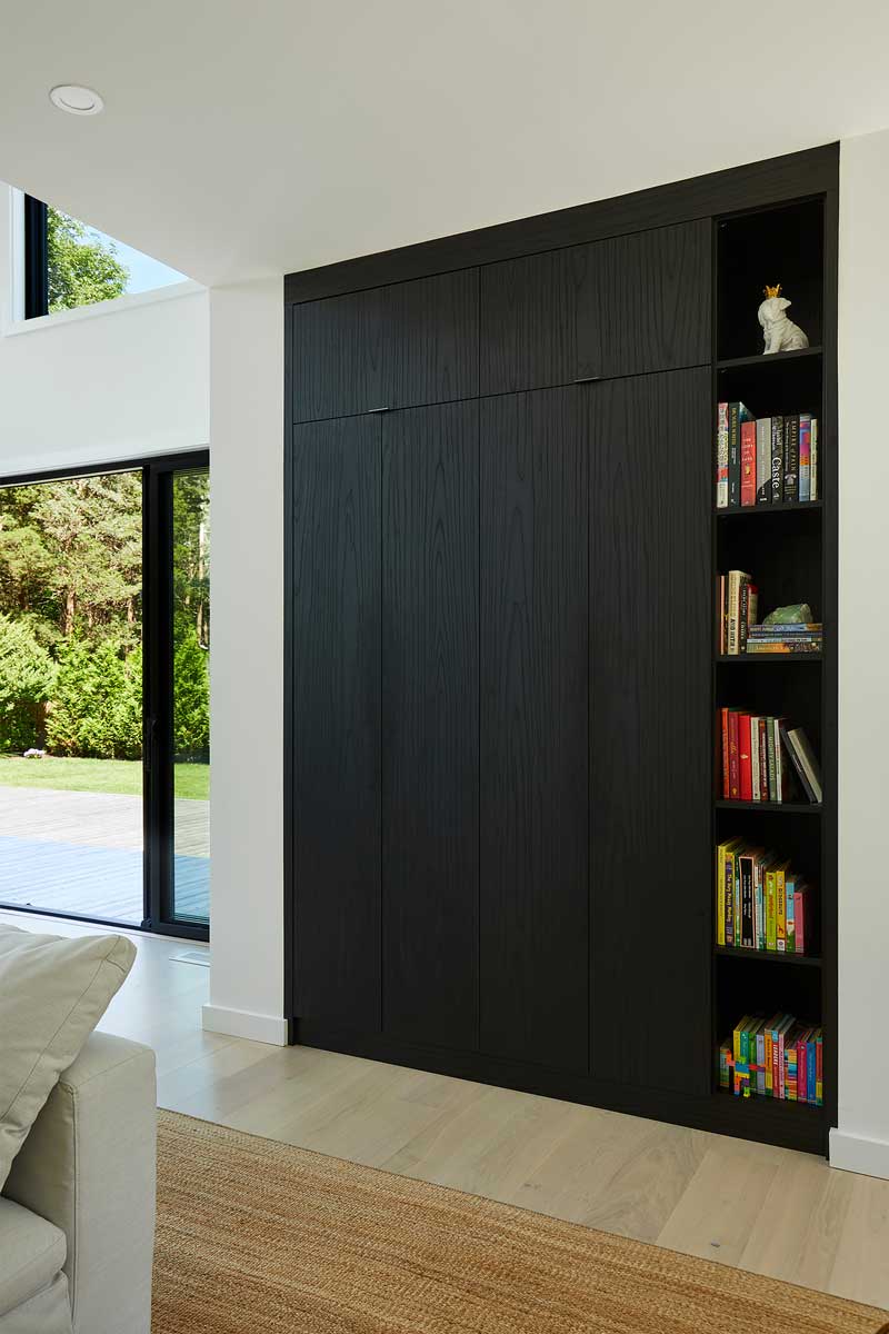 Vestavěná skříň v tmavém dřevě kombinuje úložný prostor s otevřenou knihovnou.