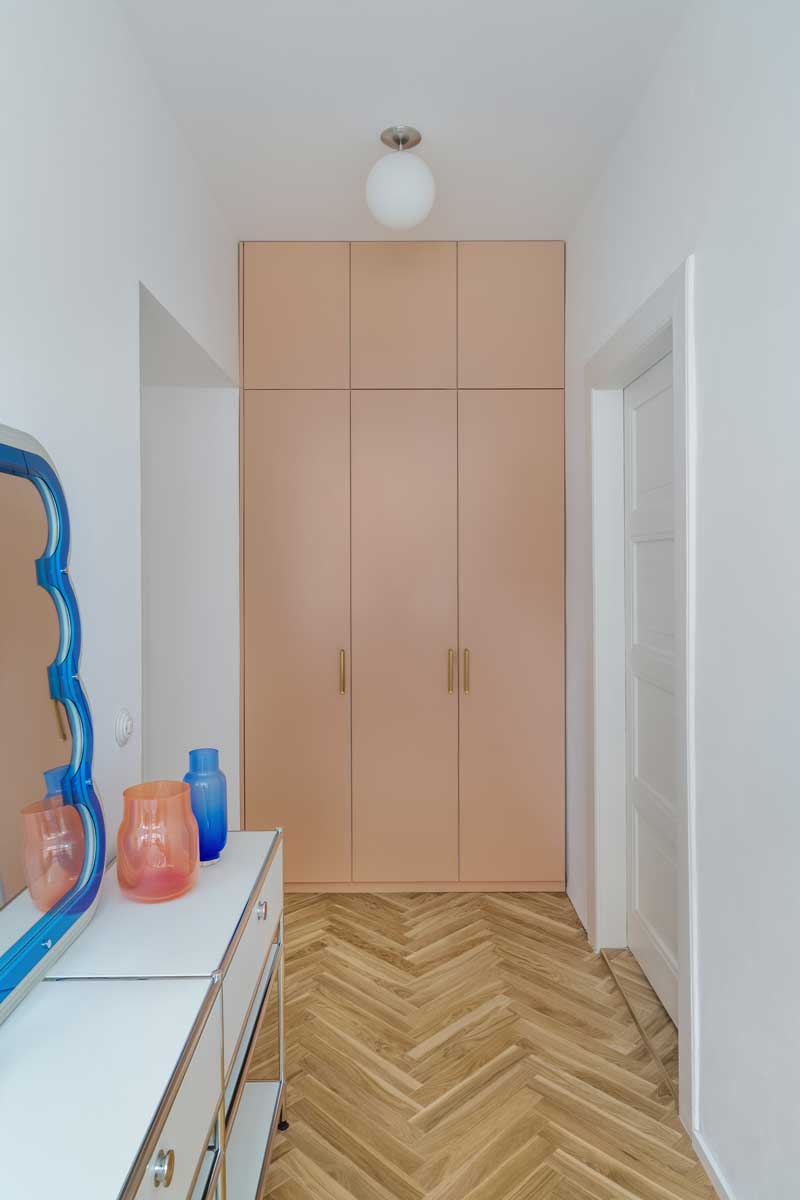Vestavěná skříň v béžovo růžové barvě v chodbě bytu s dubovou podlahou