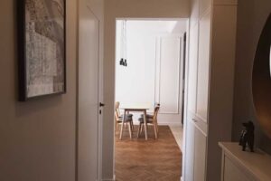 Pohled z předsíně do otevřené denní části bytu s jídelním stolem a renovovanými parketami.