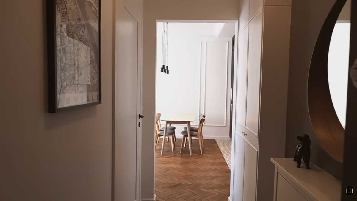 Pohled z předsíně do otevřené denní části bytu s jídelním stolem a renovovanými parketami.