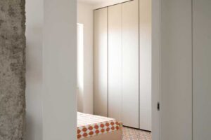 Pohled do ložnice s vestavěnou šatní skříní kde historická majoliková dlažba pokračuje i do soukromé části bytu.