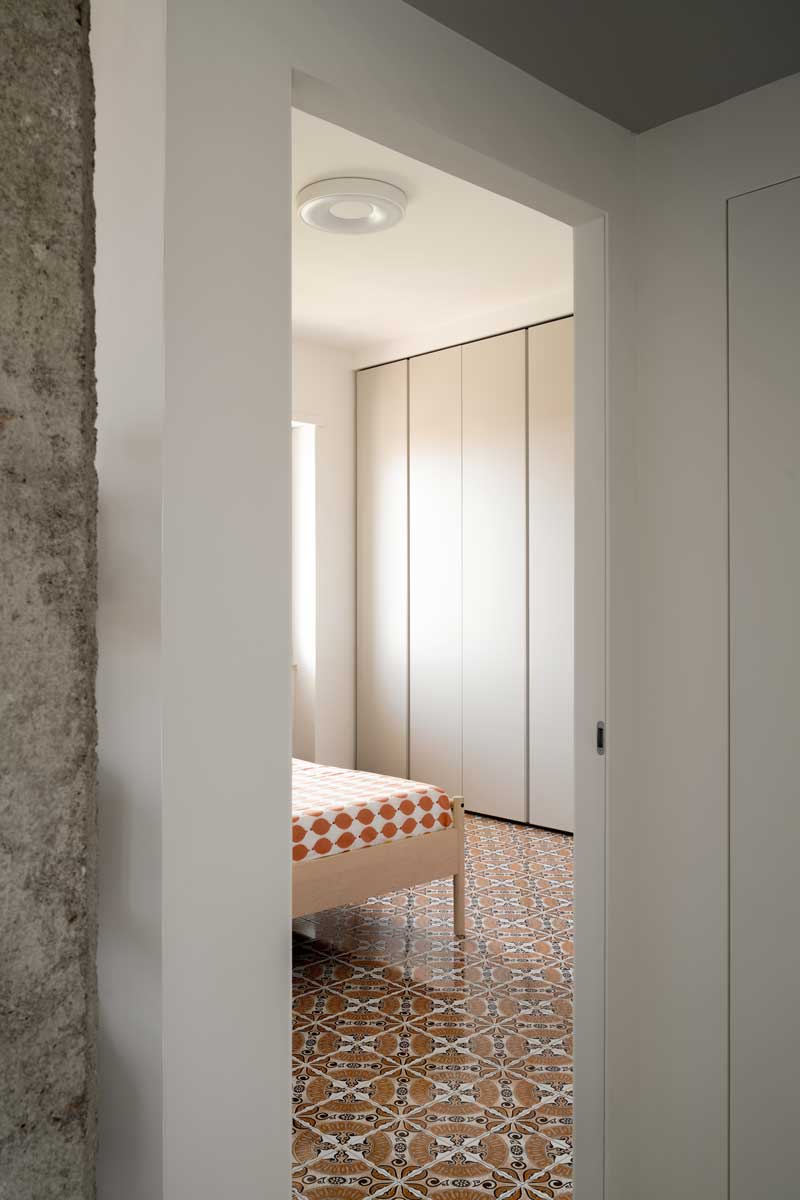 Pohled do ložnice s vestavěnou šatní skříní kde historická majoliková dlažba pokračuje i do soukromé části bytu.