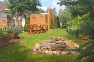 Zahrada u domu s jednoduchým ohništěm a dřevěným posezením